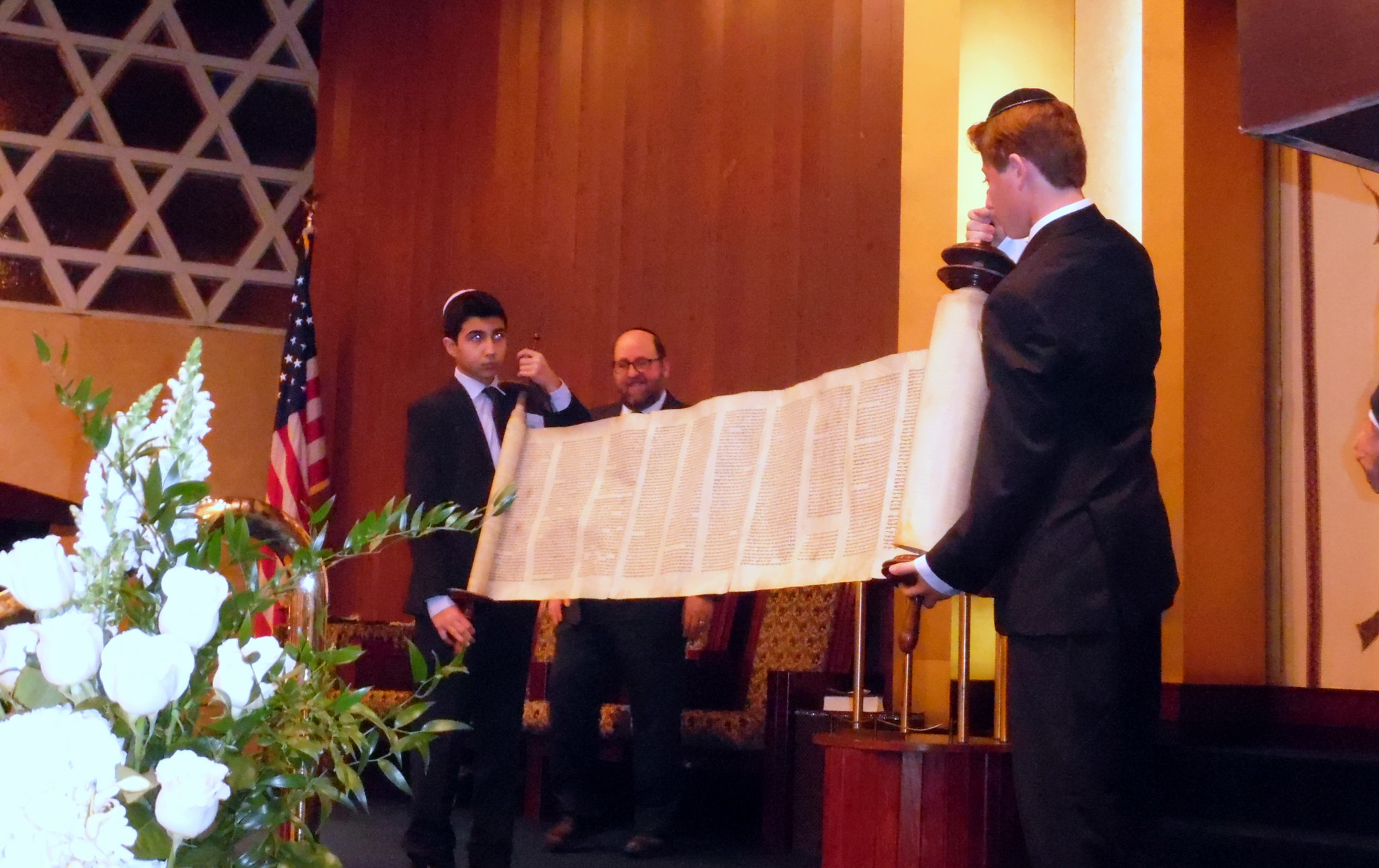 Bar Mitzvah boys Jesse Herrnson, left, and Adam Polokoff displayed the scroll at the Kristallnacht Commemoration and Torah rededication ceremony, as the temple’s Rabbi Andrew Warmflash looks on.