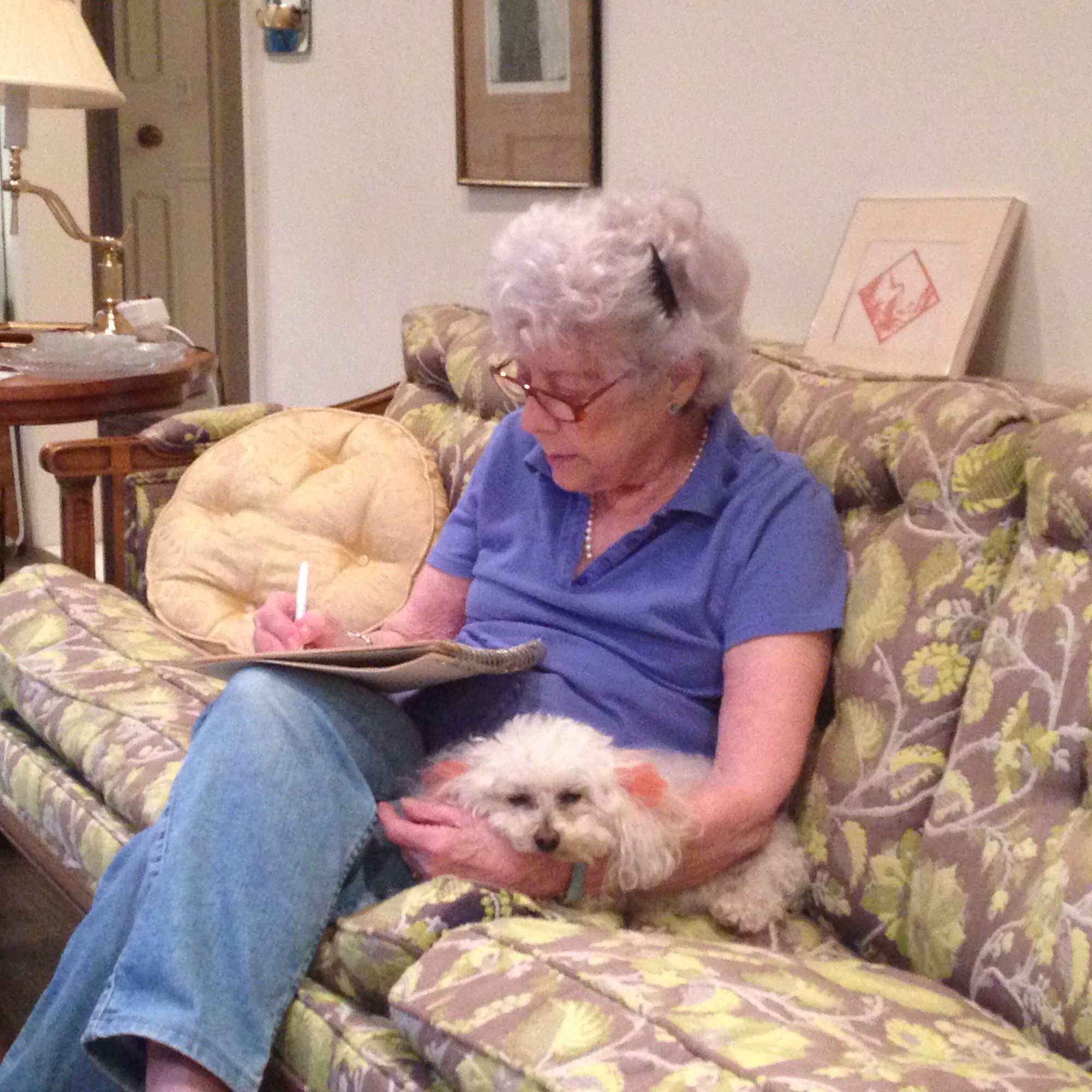 Lenore Kramer solving a New York Times crossword puzzle 
with Schnoodles snuggled next to her.