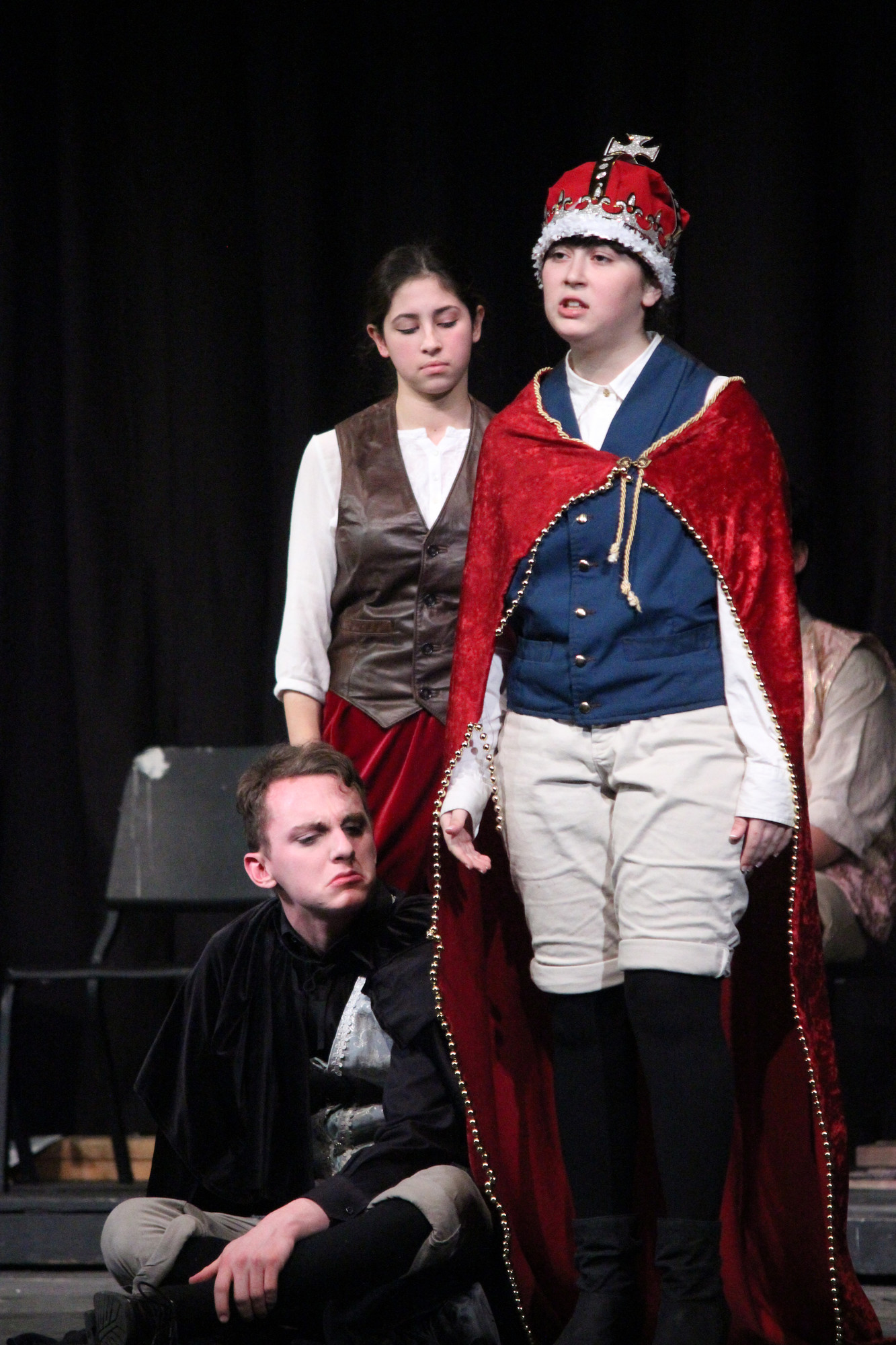 Max LoSardo,  seated, as Hamlet, listens to Horatio, played by Colette Brancaccio, and The King, played by Nadia Tavella.