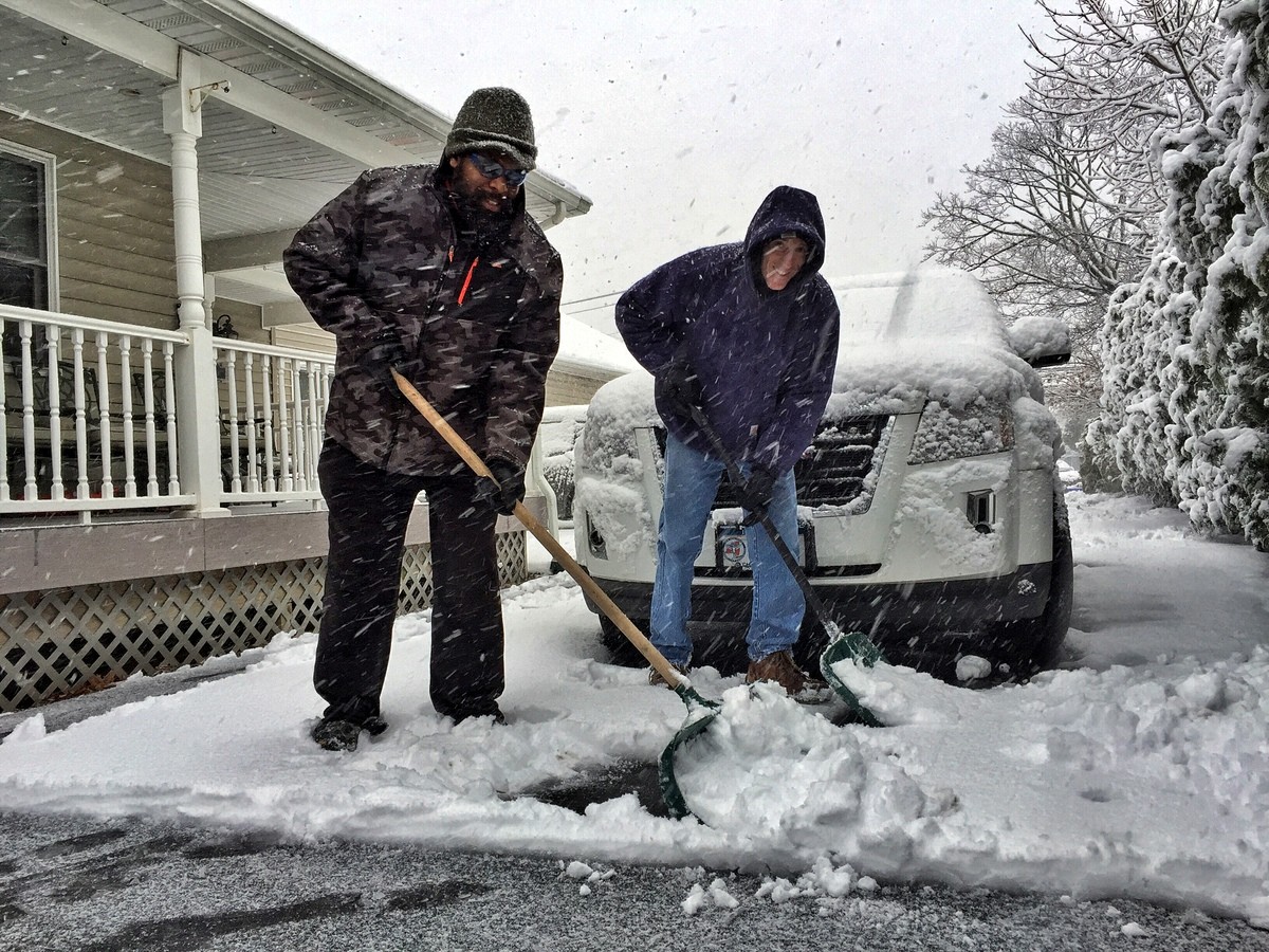Jermaine Ewell, left, and Dr. Ken Leistner clear the driveway at their Ocean Avenue office in East Rockaway.