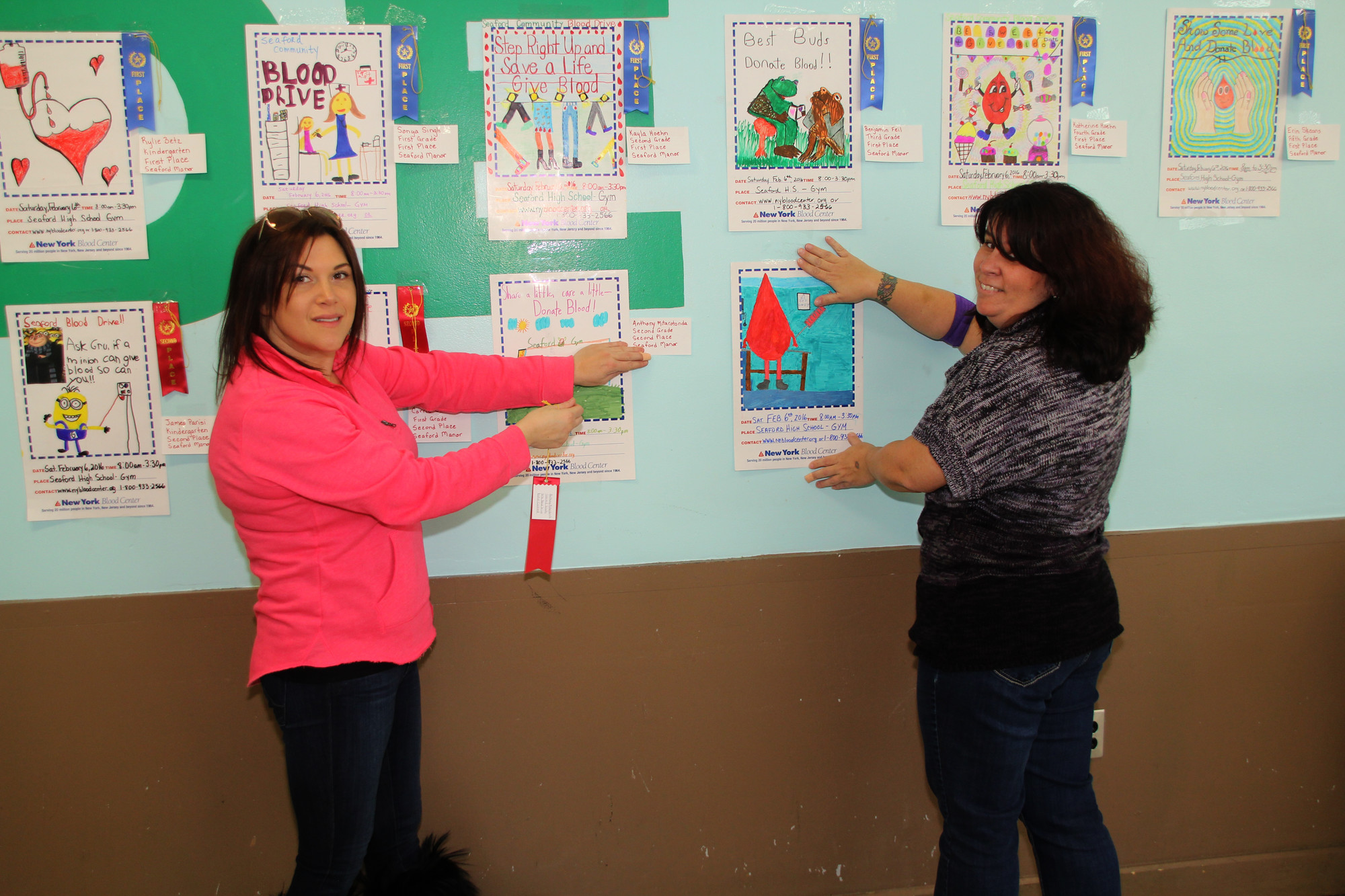 Toni Ann Sorrentino, left, and Donna D’Andrea, of the Seaford Manor PTA, got ready for the blood drive by hanging up the winning entries in the poster contest.