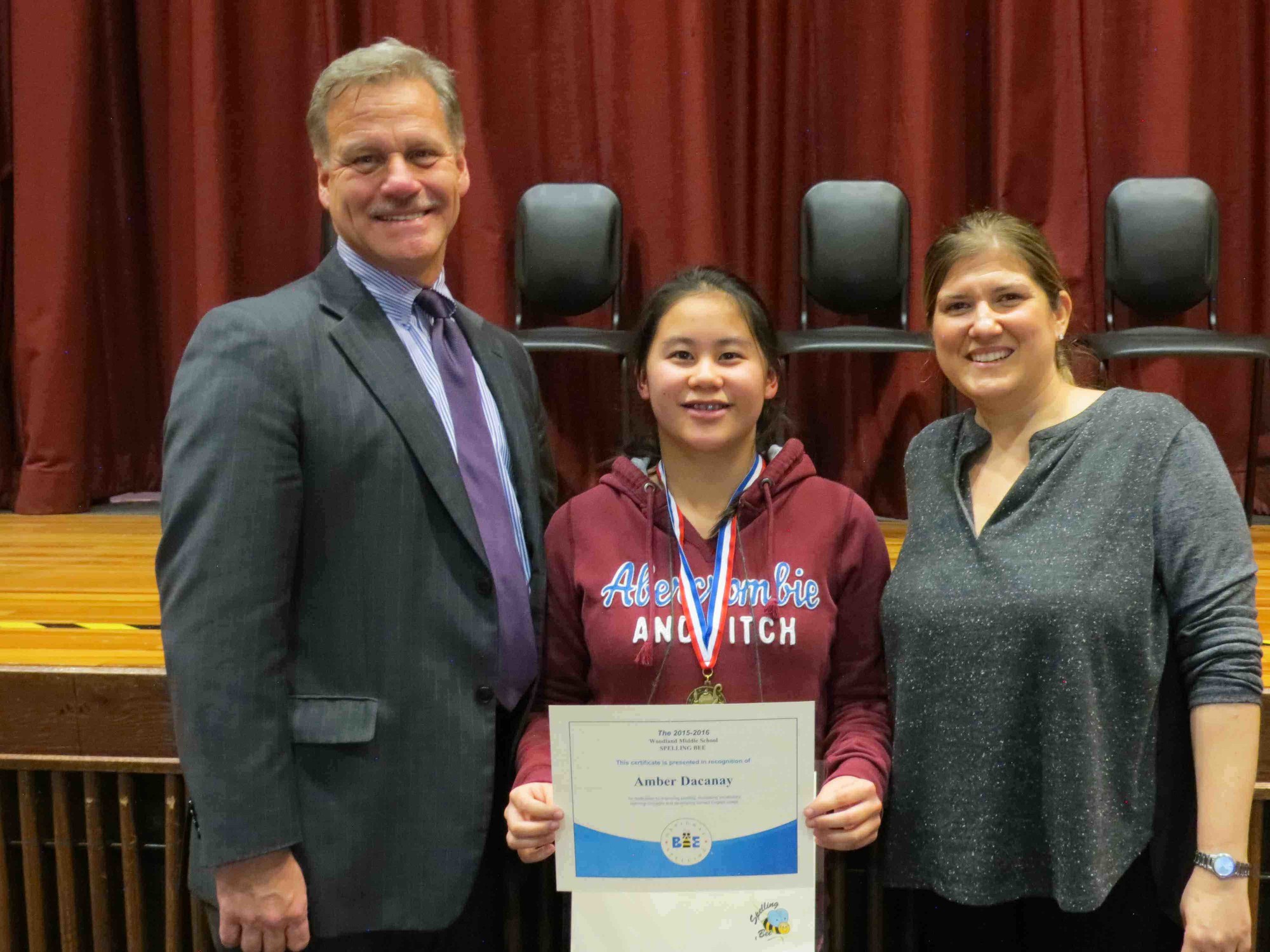 Woodland Middle School spelling bee champion Amber Dacanay met with Principal James Lethbridge and Woodland and Clarke Middle English Chairperson Rebecca Regan after she won the contest.