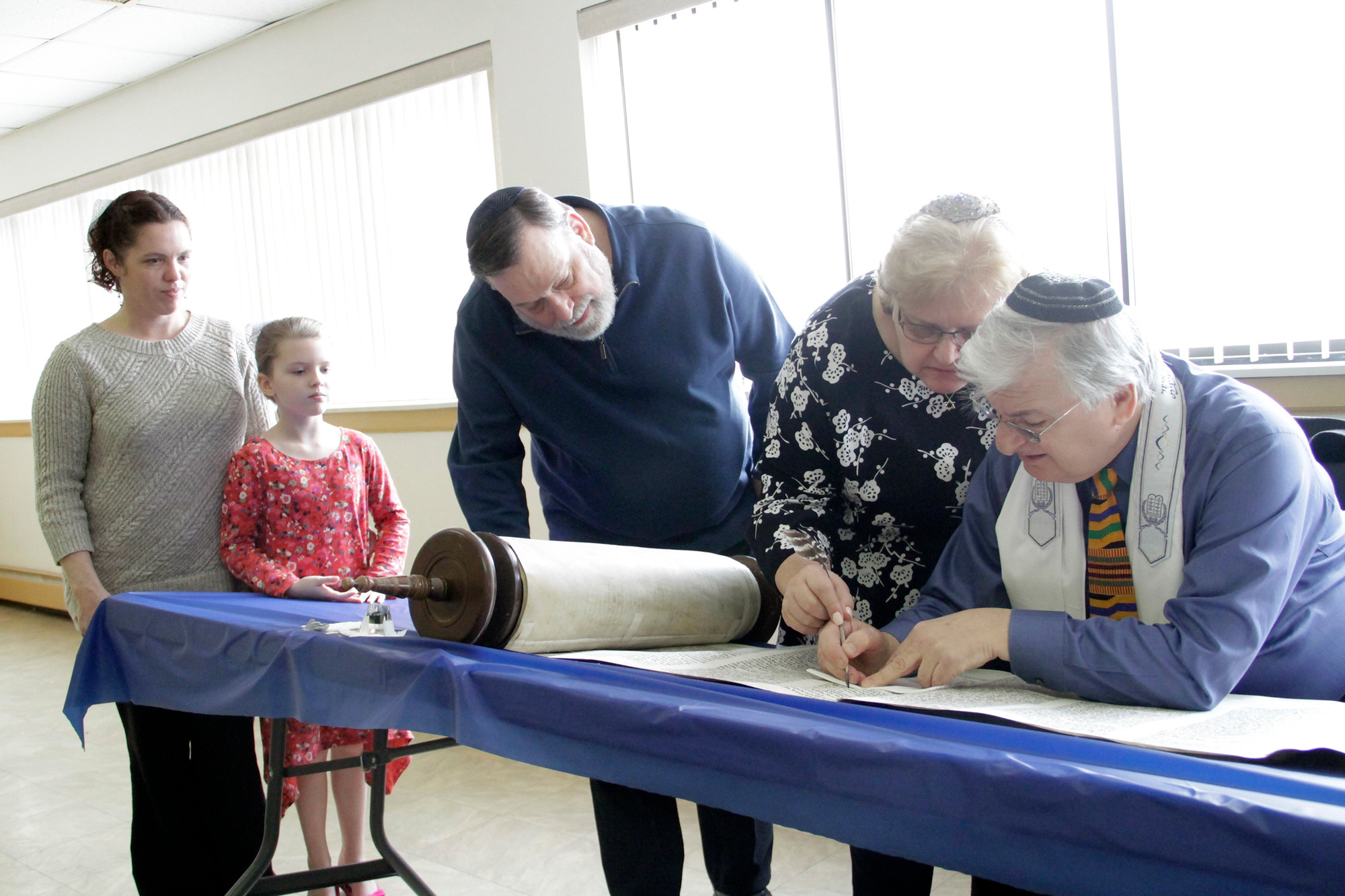 Scribe Neil Yurman, right, guided members of the Alterman family as they inscribed letters in the Torah scroll.