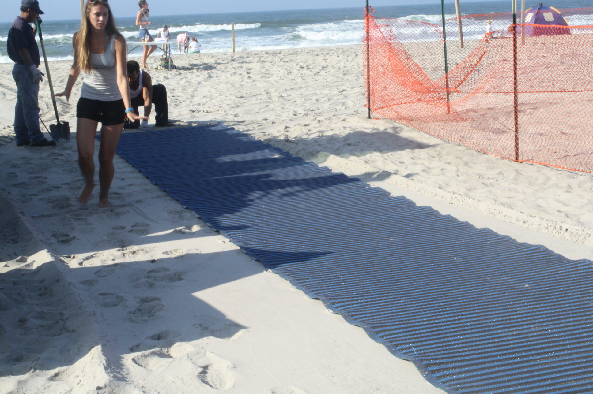The mobility mats in years past, pictured, did not extend to the water, but the city is installing longer-extending mats at four beaches this summer.