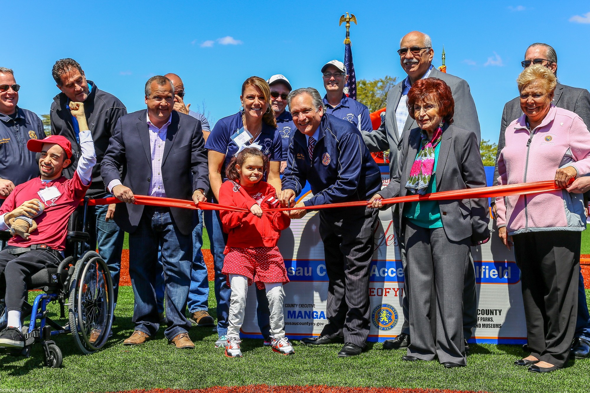 County leaders and League of YES Executive Director Kristine Fitzpatrick, center, cut a ribbon to mark the completion of the new handicapped-accessible field at Eisenhower Park on April 30.