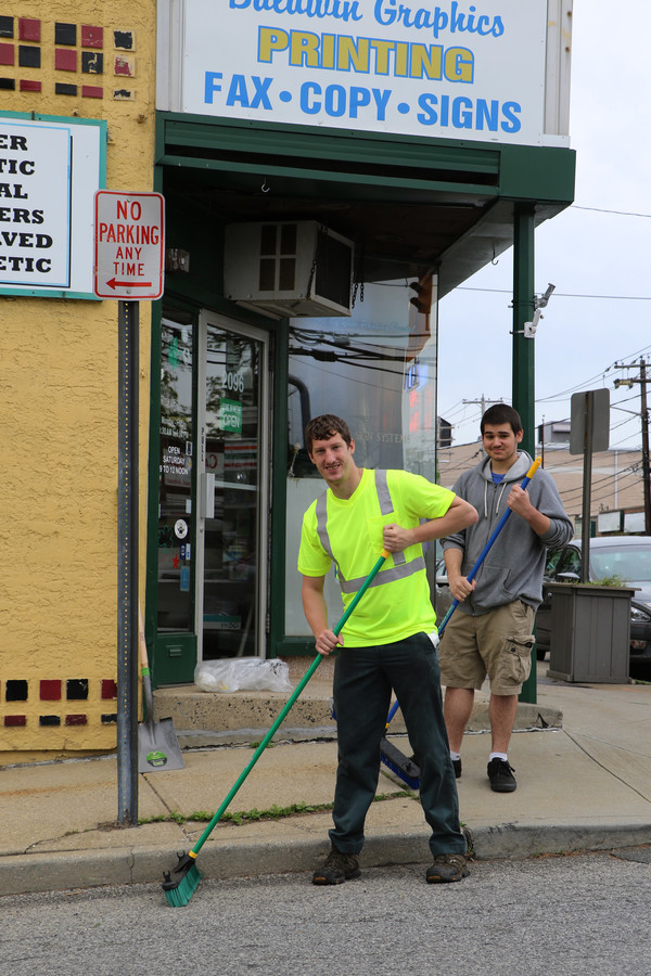 Sanitary District 2 worker Will Aleschus, center, and resident Zachary Greenwood swept up some trash on Grand Avenue in Baldwin.