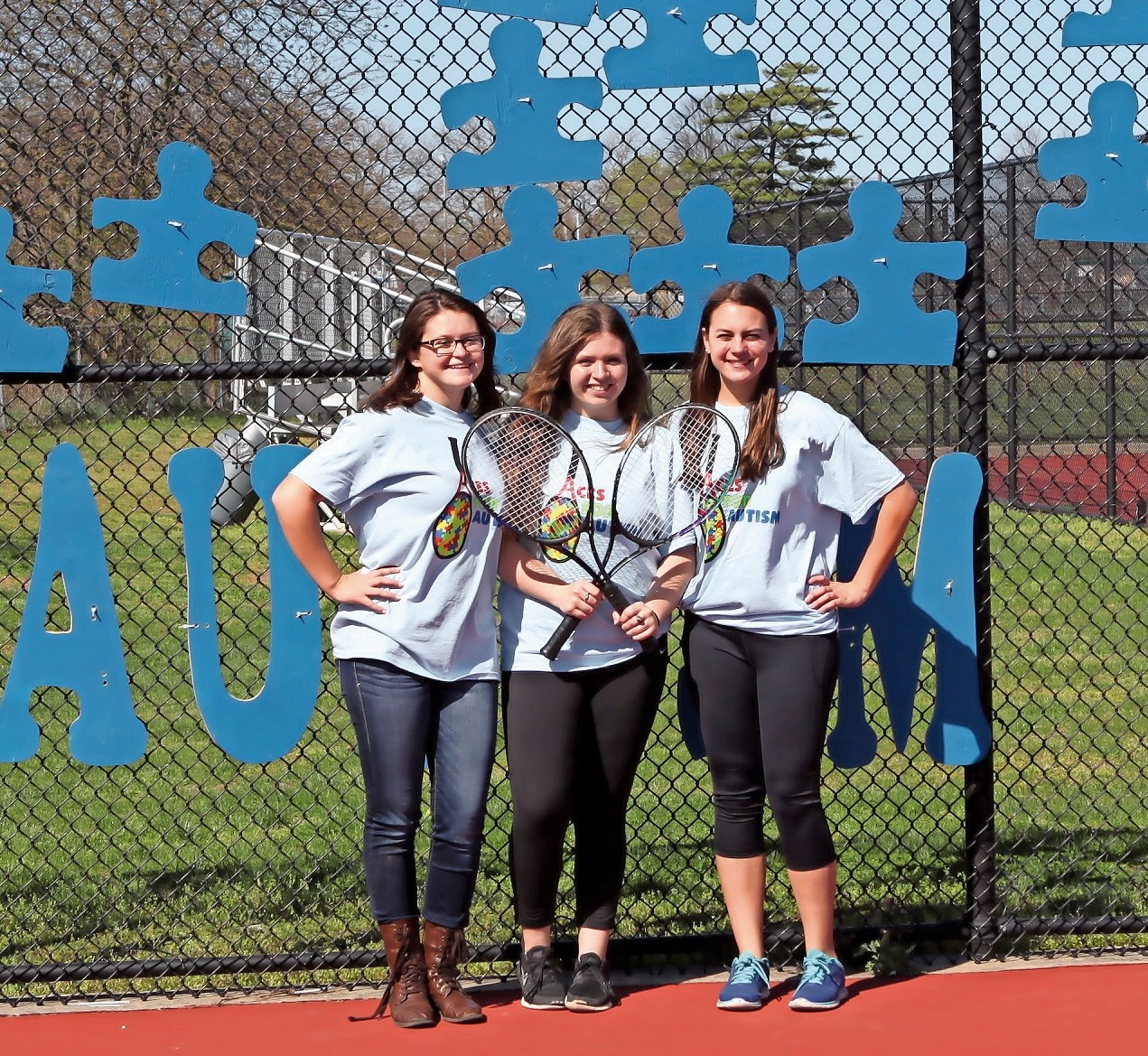 MacArthur High School tennis players Clare Del Grosso, far left, Kristen Cassidy and Alyssa Breeze participated in Aces for Autism, the team’s clinic for students in the Applied Behavior Analysis program, in April.