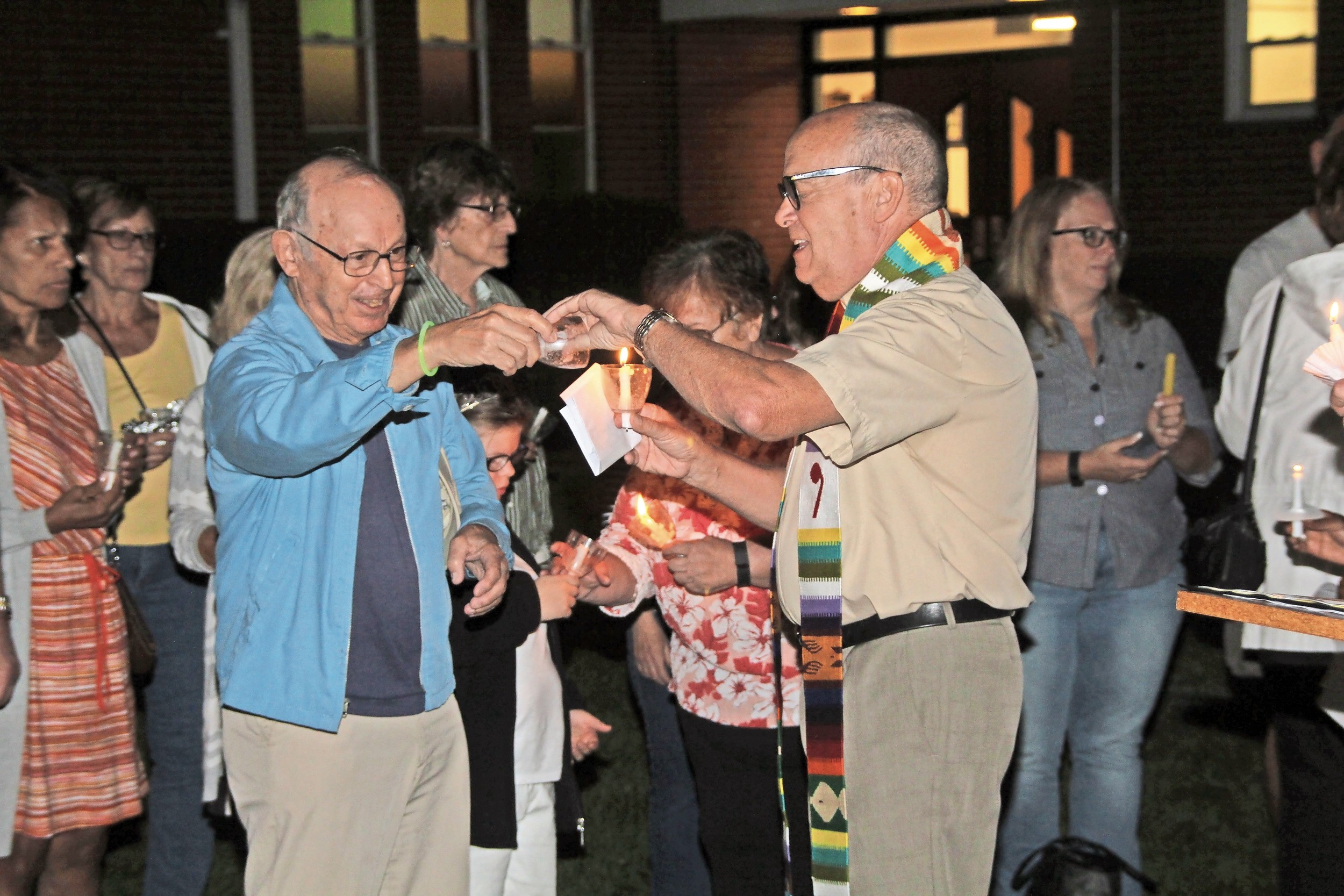 The Rev. Ron Garner, right, pastor of Wantagh Memorial Congregational, lit residents’ candles using one flame to show that the community is united.