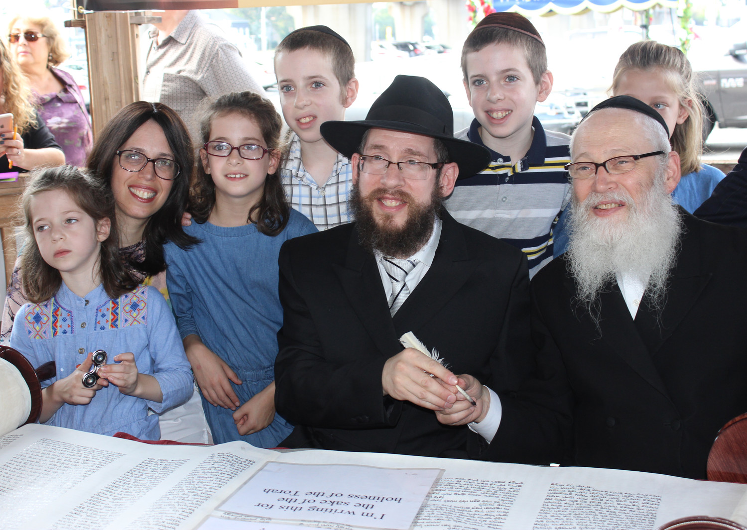The Chabad Center finished drafting its new Torah scroll in the Merrick train station gazebo on Sept. 17. Above, from right, were Rabbi Moshe Klein, the Torah’s scribe; Kramer; his wife, Chanie; and their children, from left, Leah, 6, Mirel, 8, Binyamin, Leibel, and Sarah, 8.