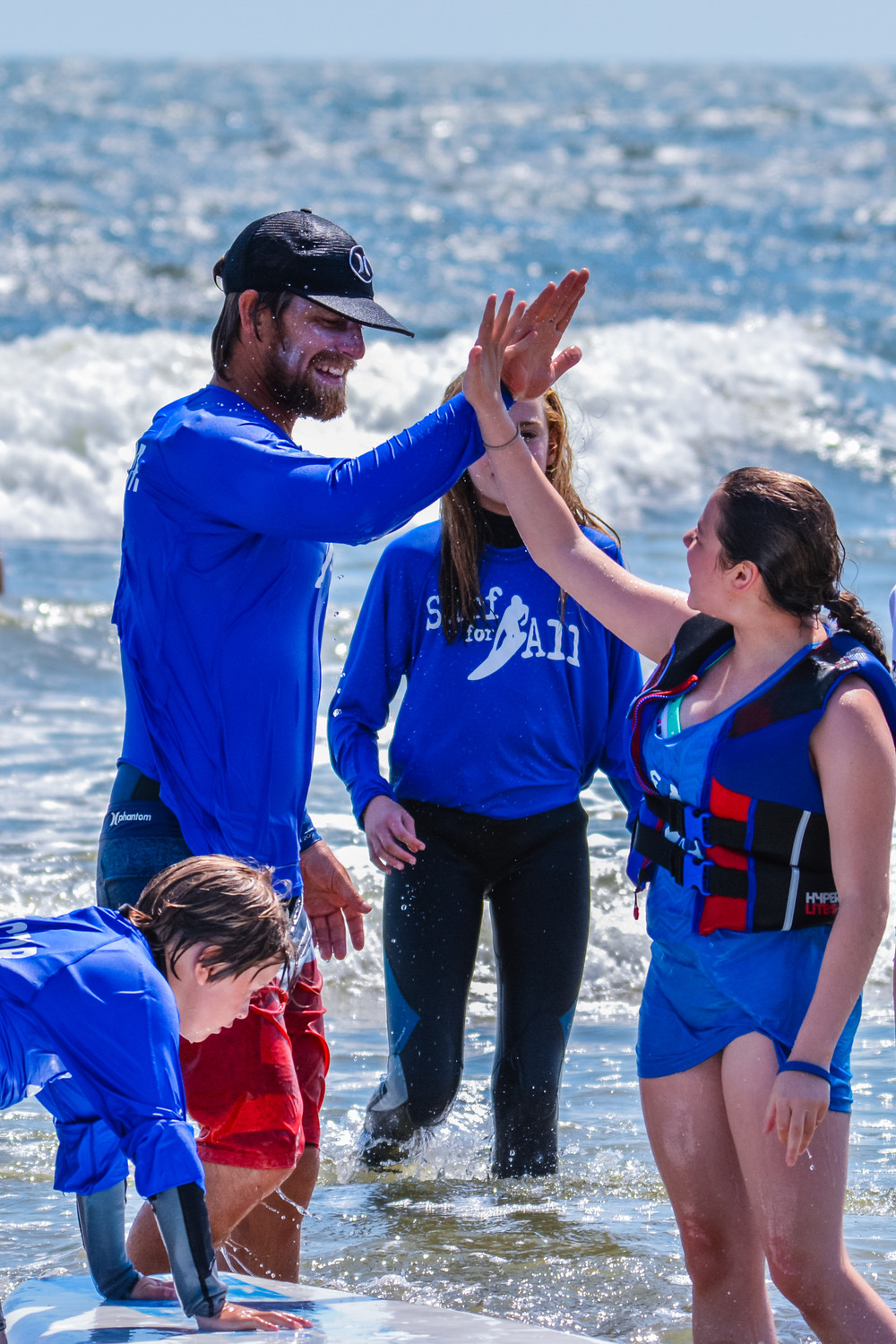 Professional big-wave surfer Will Skudin celebrated with a student during a Surf for All outing in 2015.