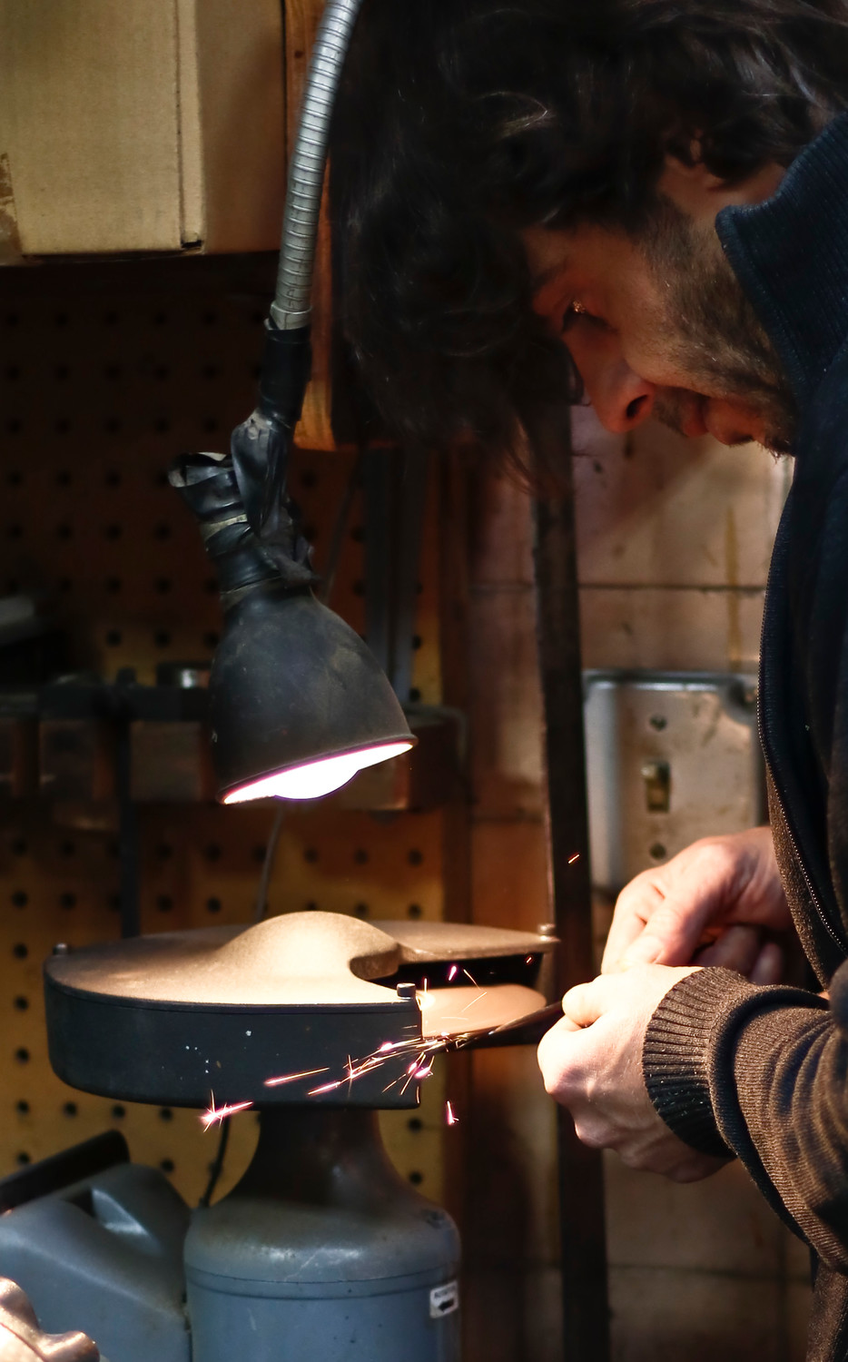 Simone Diana hones the chisel he is using to carve the edges of a new bass.