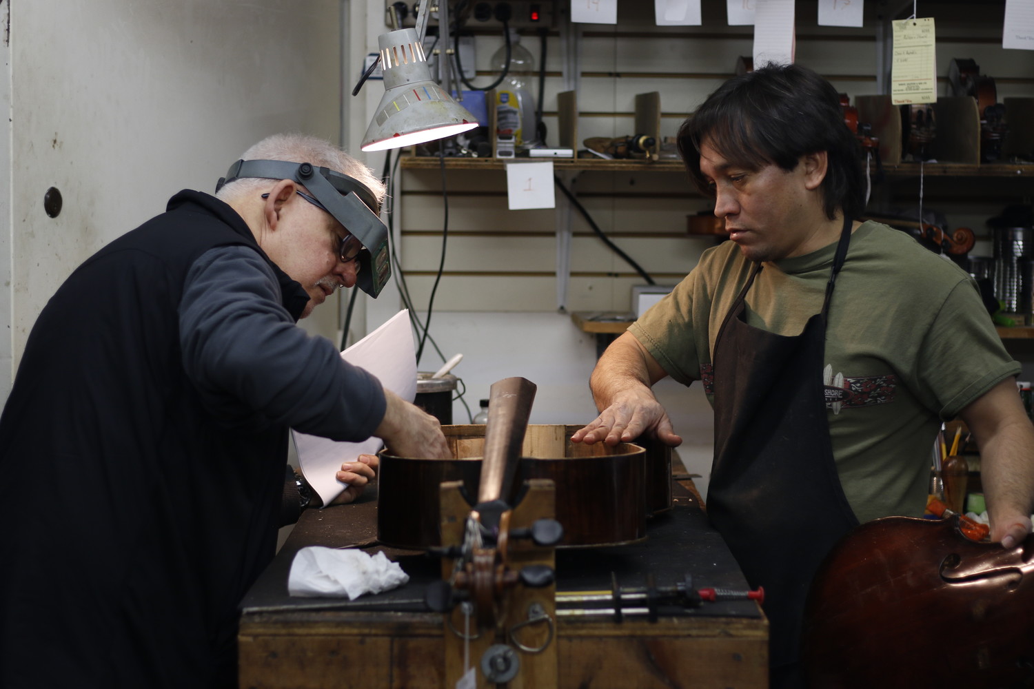 Jake Cradilas and Ricardo Hernandez make a final examination of the repairs before gluing the cello back together.