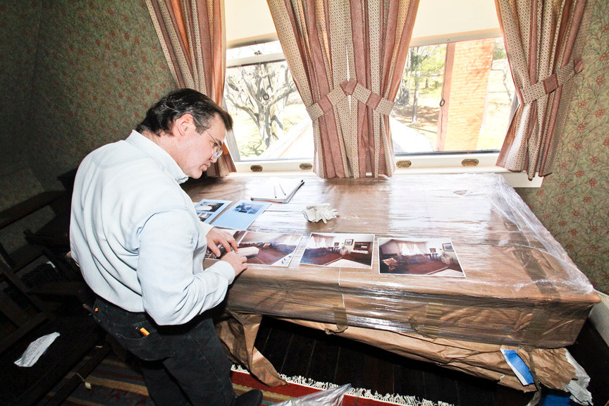 George Hagerty looks over the photos of TR Jr.'s room before starting on the reconstruction. Every room was photographed from all angles so everything can go back exactly how it was before the rehabilitation started.