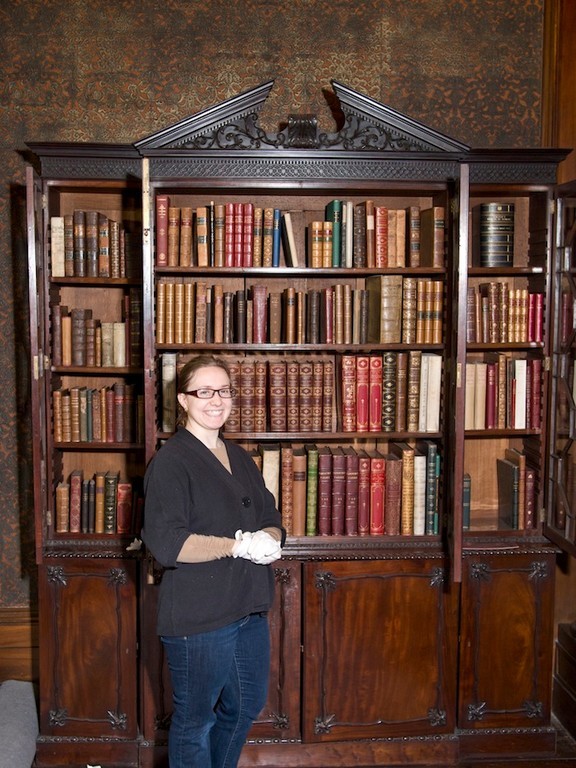 Sag. Hill House Archivist - Betsy DeMaria in front of one of the many bookcases n the North Room of Sag. Hill.