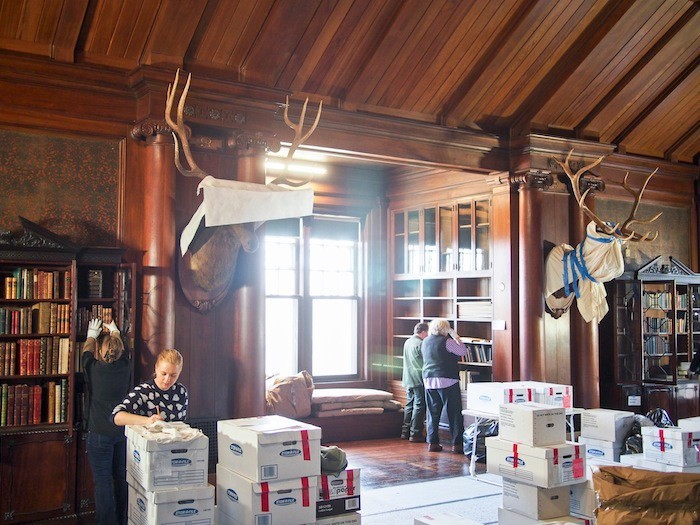 Workers and volunteers in the North Room of Sagamore Hill. Boxes of books need to be replaced in bookcases in the specific order in which they were removed.