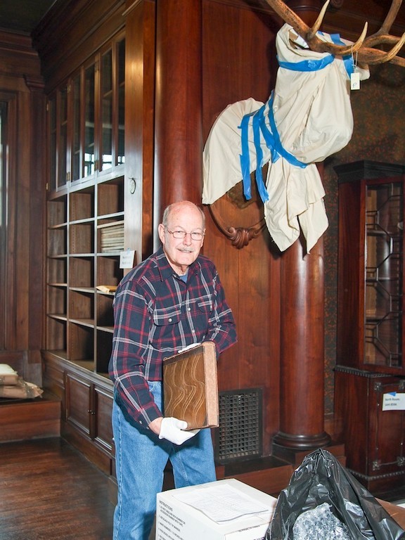 William Hall, a volunteer, unpacking books in the North Room of Sagamore Hill. Books need to be replaced in bookcases in the specific order in which they were removed.