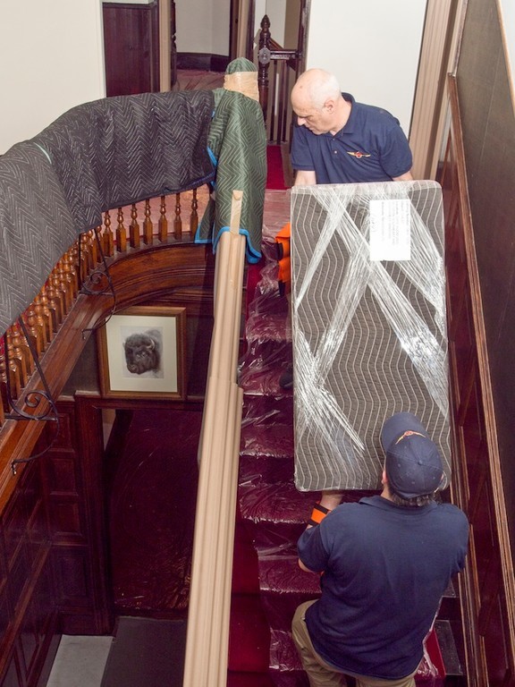 workers from U.S.Art carry a mahogany chest still in plastic wrap, up the stairs for placement in the "Gate oRom" on the 2nd floor.