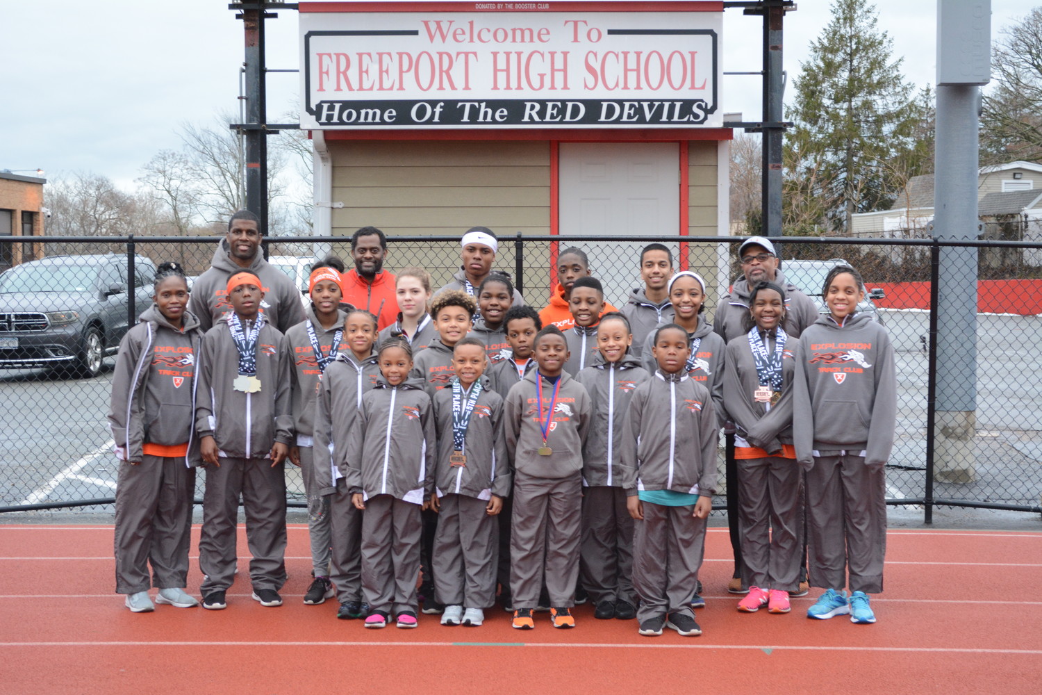 Athletes and coaches from the Explosion Track Club with their medals on the track at Freeport High School, where they practice.