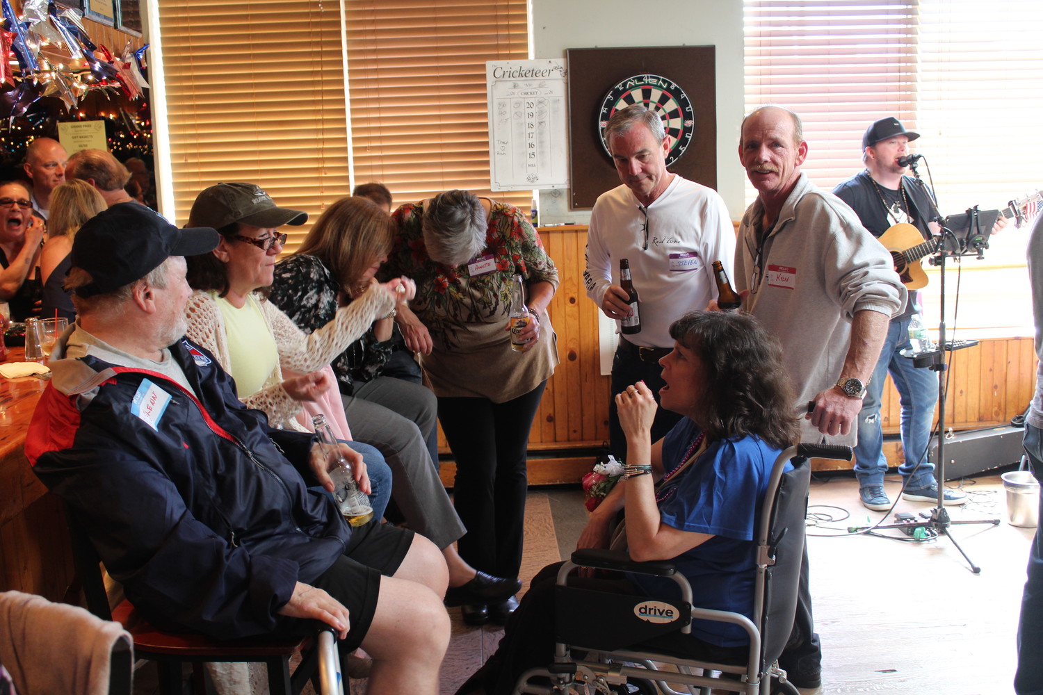 Joan Greenspan, seated at right, caught up with old friends at a June 3 fundraiser held to collect money for her purchase of a handicapped-accessible vehicle. Greenspan has multiple sclerosis and cannot leave her home without assistance.