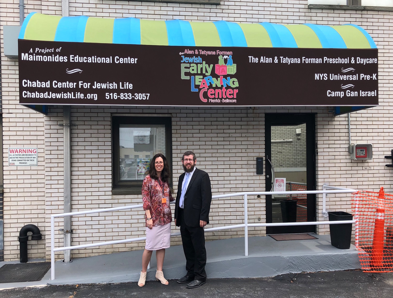 Rabbi Shimon Kramer and his wife, Chanie, under the new awning over the entrance to the Jewish Early Learning Center.