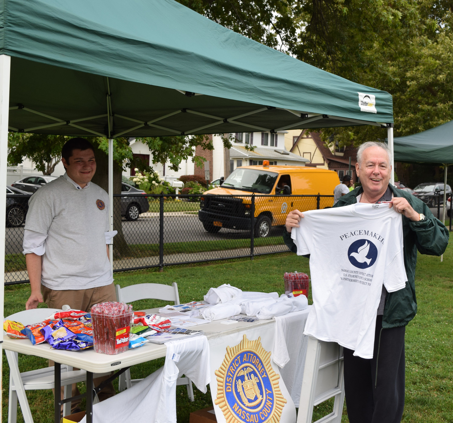 George Heino showed off the swag he picked up at National Night Out at Andrew J. Paris Cedarhurst Park. At left, fellow Woodmere resident Yitzchak Carroll, a Nassau County District Attorney office liaison.