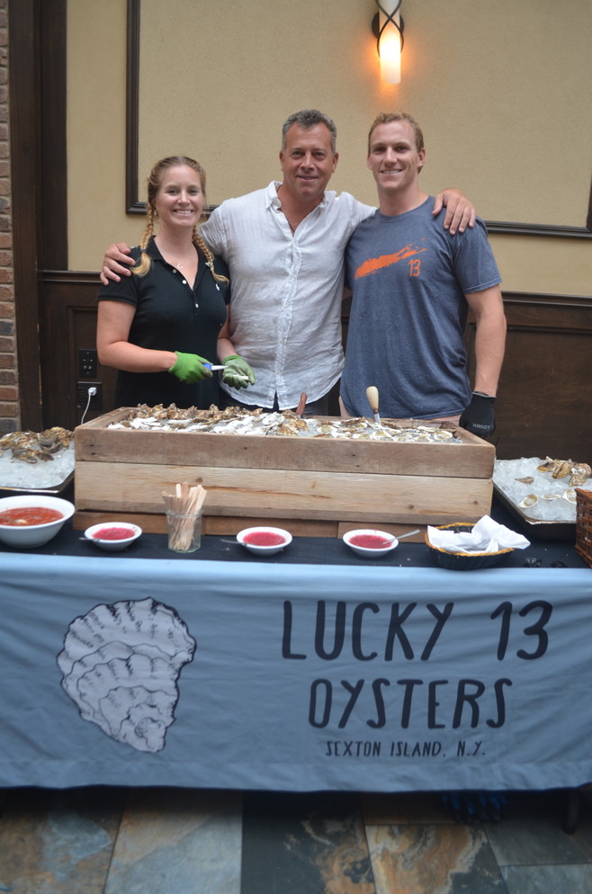 Kate Sheil, left, and Pat Joy from Lucky 13 Oysters flanked festival organizer Terence Mulligan after serving oysters to guests.