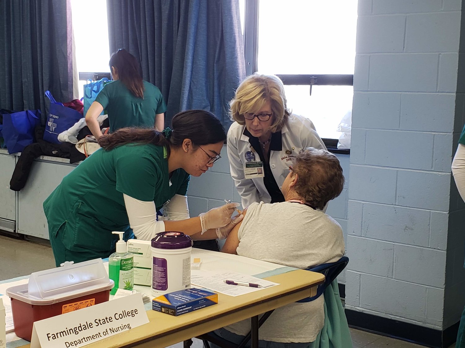 Farmingdale State College nursing student, Karla Chelsea, left, administered a flu shot to Freeporter Margret Bade, 76, right, while Assistant Professor from the Department of Nursing, Monica Diamond, center, instructed and supervised Chelsea.
