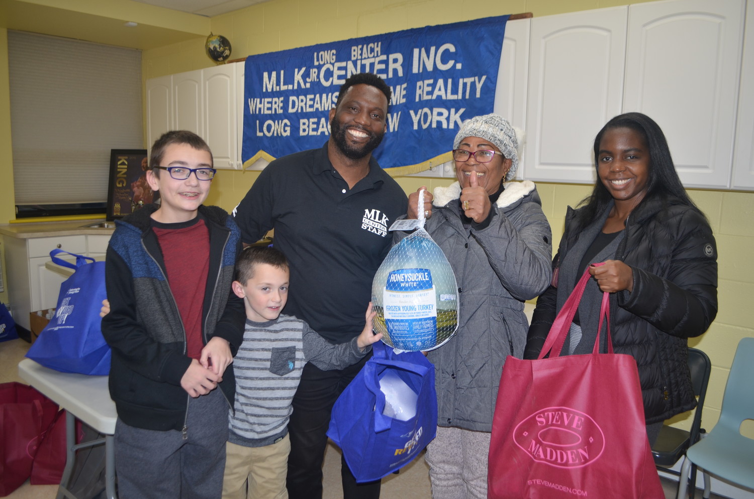 Jacob Hurney, left, Luke Santeramo, Martin Luther King Center board Chairman James Hodge, and Andrea Wilkins, far right, handed a turkey and a bag of traditional Thanksgiving dinner trimmings to Long Beach resident Milagro Rodriguez on Tuesday.  