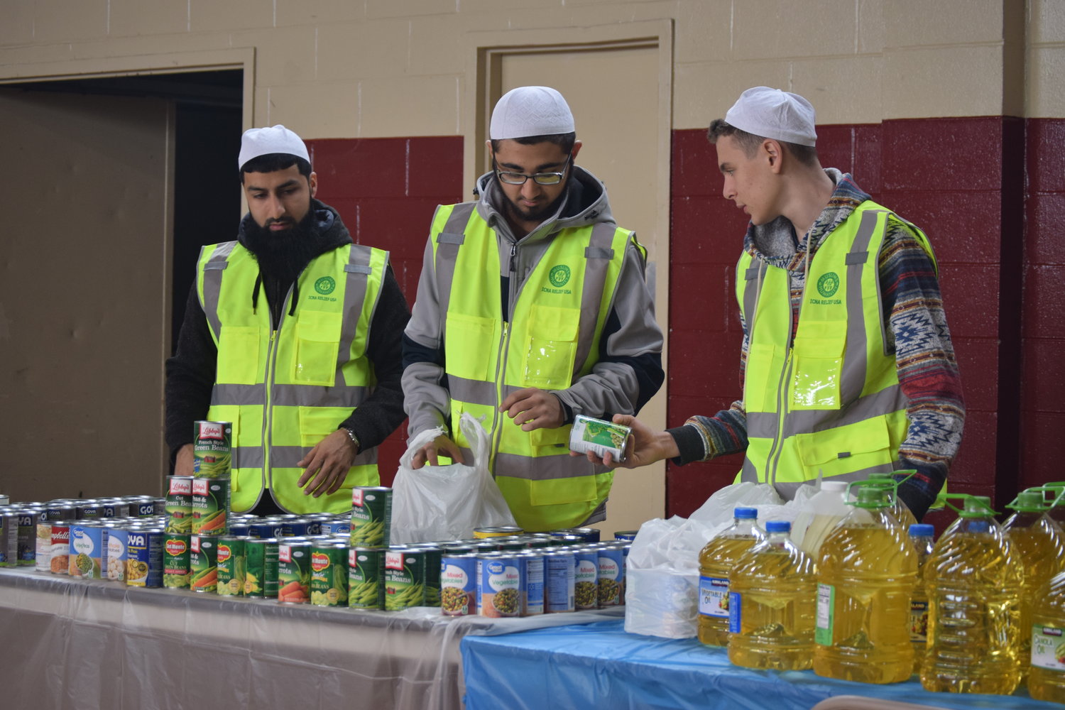 ICNA Relief volunteers Umar Chaudry, Addullah Qureshi and Taib Iraqui-Houssain put out the canned goods at the holiday giveaway.