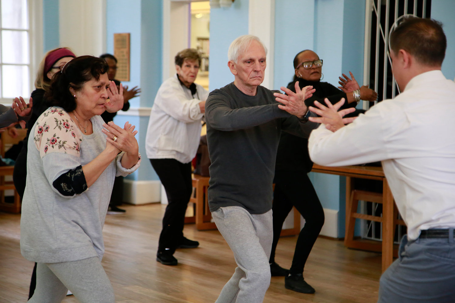 Tai chi students, Olga Marrell, left, and George Perfetto follow instructions during the ward off movement.