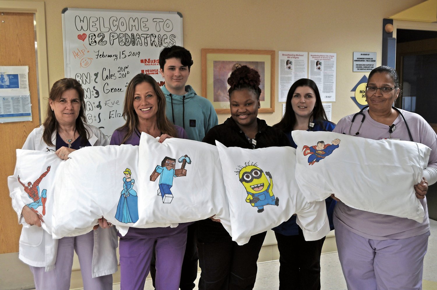 Nicholas Bolognini, third from left, drew cartoon characters and superheroes on a dozen pillowcases, which he donated to South Nassau Communities Hospital’s Pediatrics Department as a way to bring cheer to sick children. Bolognini was inspired by his cousin, Jessica Gruenfelder, who underwent four brain surgeries at the hospital after suffering two strokes. With Bolognini were South Nassau team members, from left, Lynn Bert, a nursing manager; Grace Maleweicz, a nurse; Shante Williams, a nursing assistant; Elizabeth Feil, a unit clerk; and Dawn Coles, a nurse.
