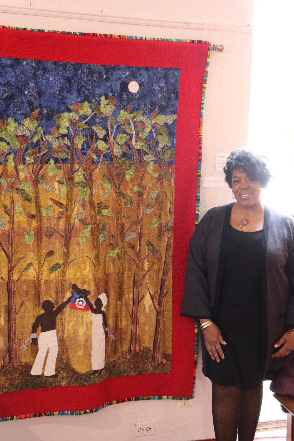 Kim Taylor with her quilt “Juneteenth,” representing the day the United States abolished slavery, one of her many creations on display at Freeport’s South Nassau Universalist Congregation.