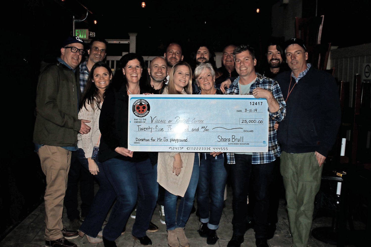 Members of Taking Back Sunday and the Tommy Brull Foundation held a check for $25,000 to be donated to Mr. B’s Playground.