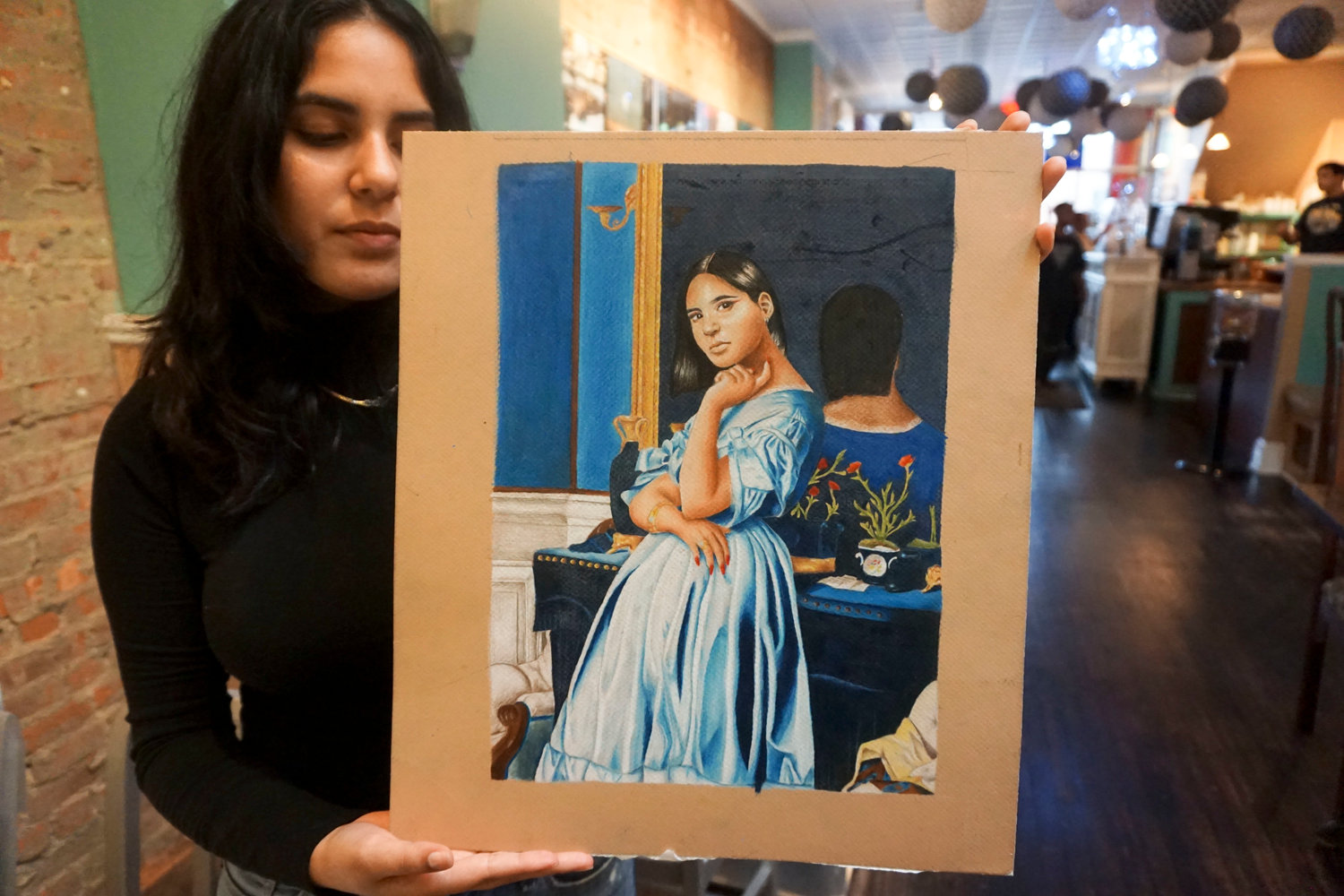 Recent Central graduate Paula Guevara with her favorite self-portrait, which she worked on for five months.