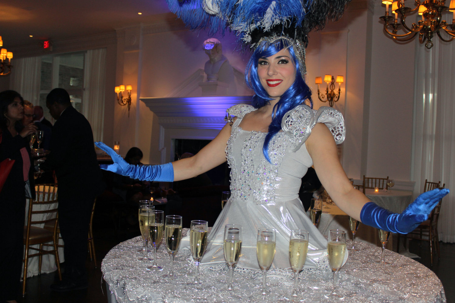 A performer wore a shimmering “champagne dress” that was fastened to a table and lined with glasses of champagne that she served to guests.