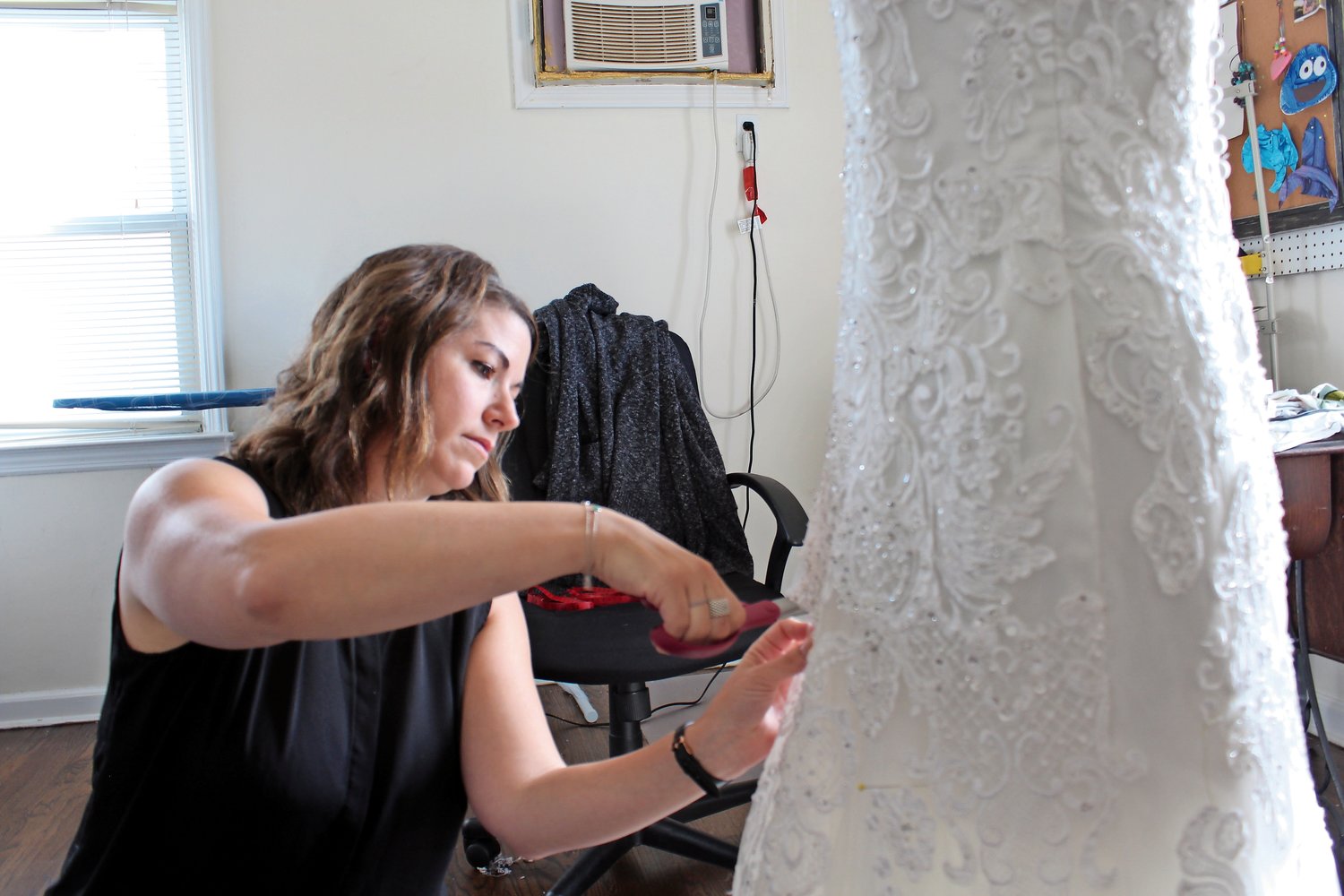 Cat Munzing cut a client’s dress, the first step in repurposing it to create a christening gown for the woman’s daughter.