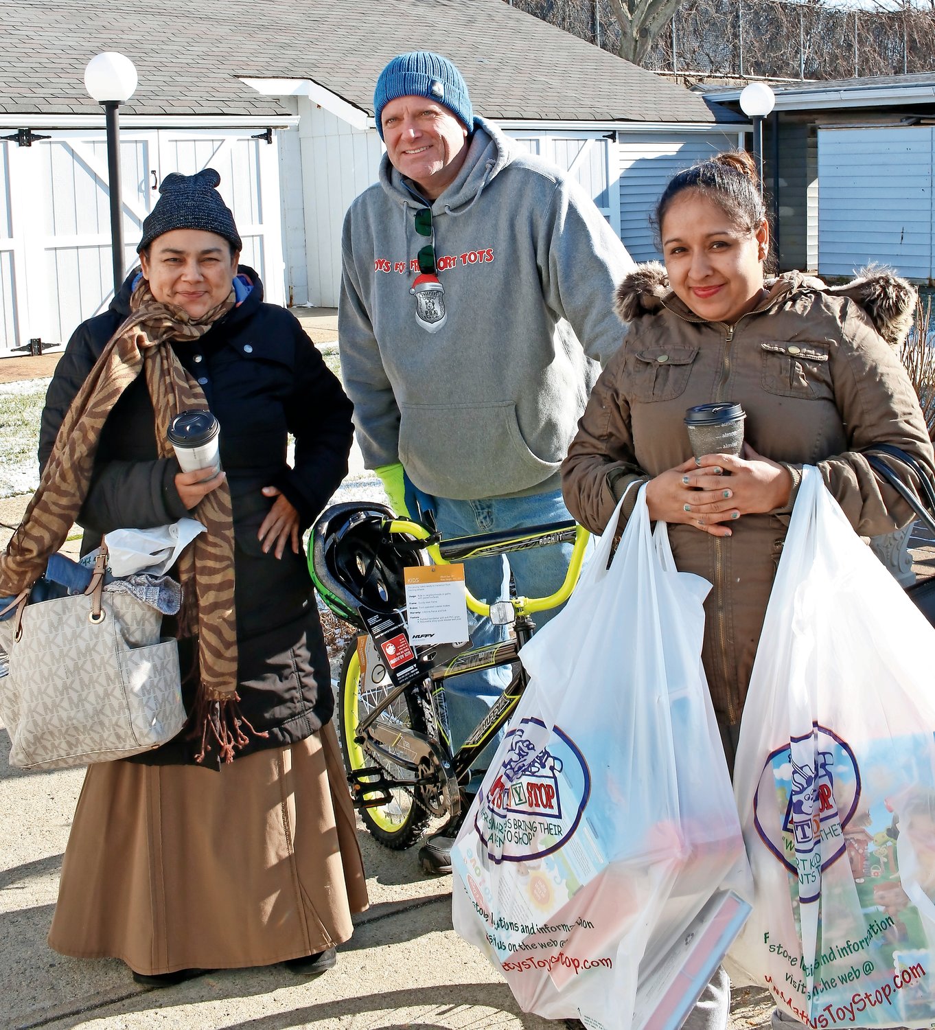 Franzone, center, brought a bike to Marlana Recen-Hernandez, left, for her son. Her friend Amalia Argueta, right, helped her carry a bags of toys to her car.