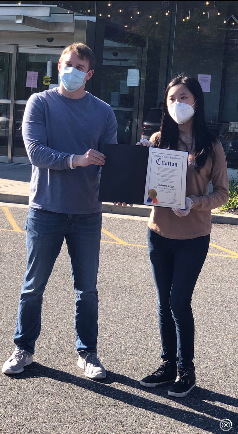 Josh Lafazan, left, awarded Sabrina Guo with a citation of recognition for her work in the PPE relief effort, as well as coordinating cards and artwork for health care workers.
