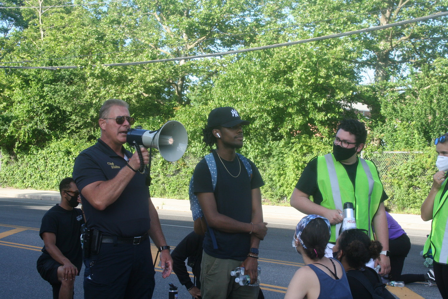 Glen Cove Police Chief William Whitton, left, told the crowd he supported them but would not kneel as Antwan Brown and protest organizer Stevens Martinez listened on.