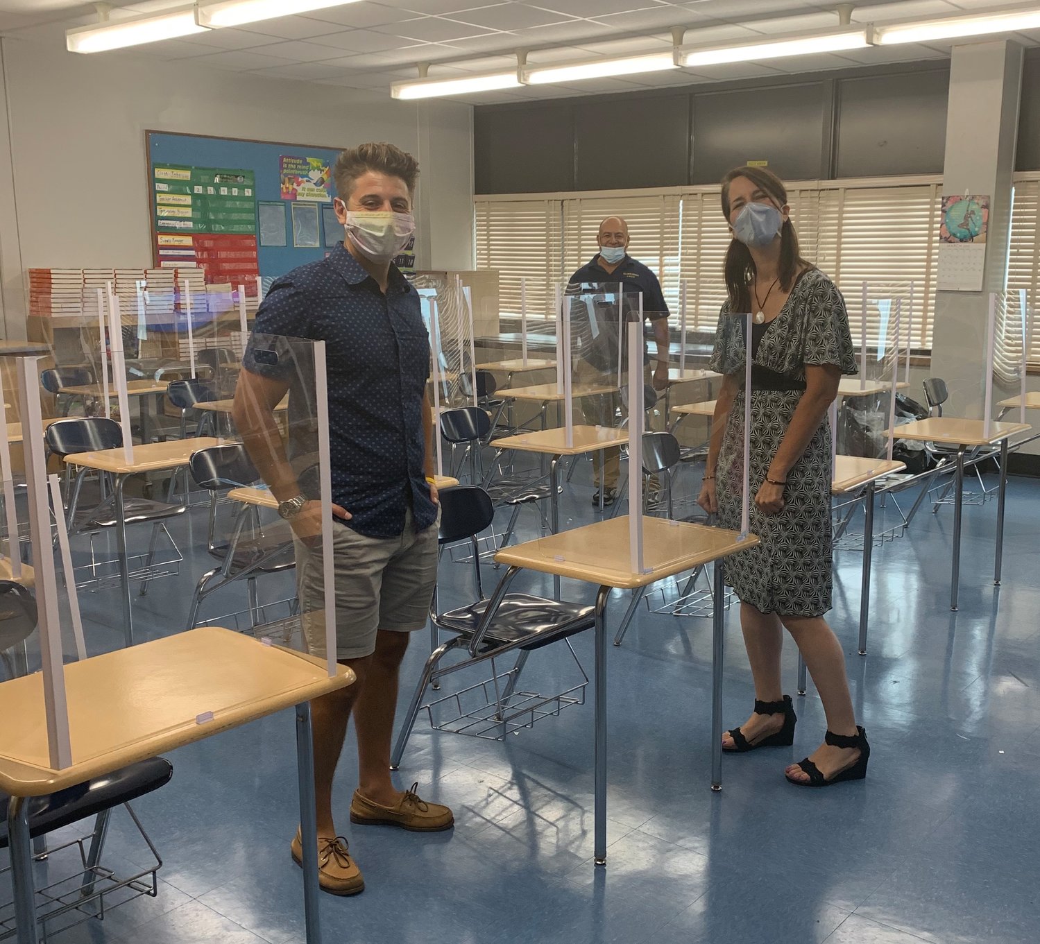 Calhoun High School teachers Michael Pisano and Beth Finneran set up their shared classroom as custodian Abel Gomez put finishing touches on the desks’ plastic barriers.