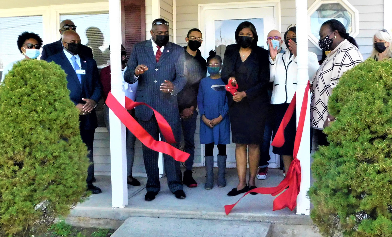 Jarren and Kailyn Style look on as their mother, Kimberly Style, cuts the ribbon to inaugurate their new home. Applauding them are Hempstead Mayor Waylyn Hobbs, Jr., and other dignitaries.