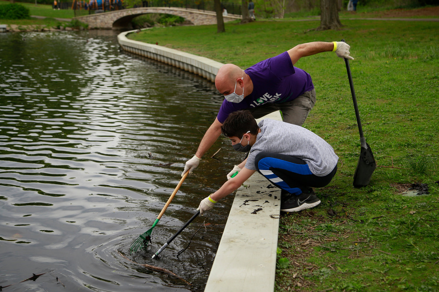 Volunteer Logan Shinsato, 12, and his father, Ivan, teamed up to loosen a pile of debris in the pond.