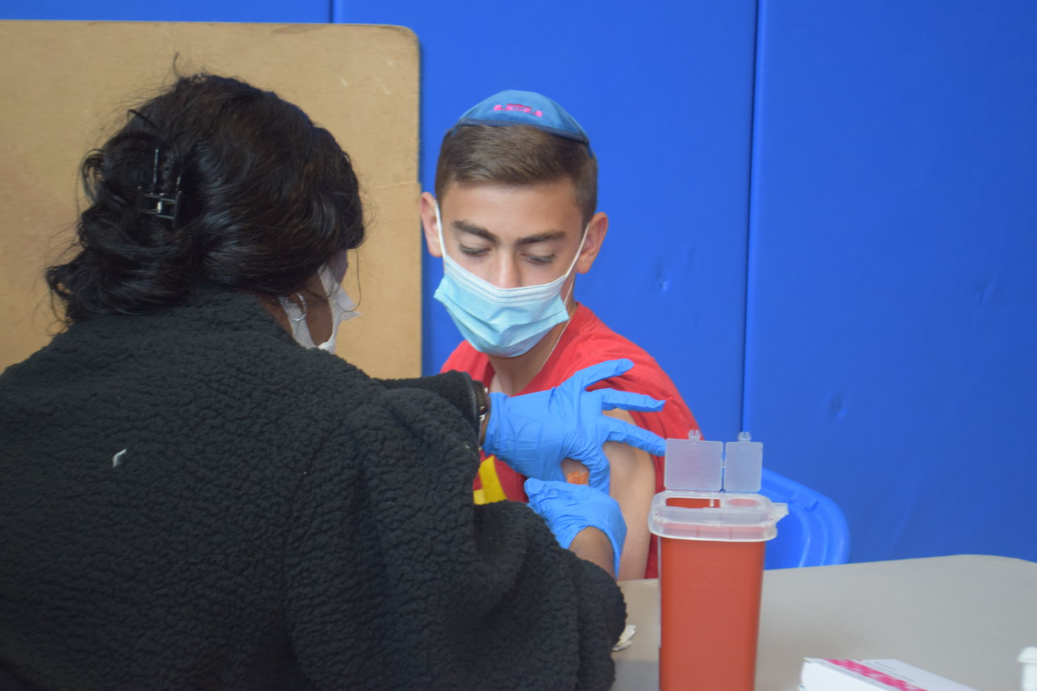 Onsite Medical Solutions nurse Tanya Vowes administered the Pfizer-BioNTech vaccine to Yeshiva of South Shore eighth-grader Adir Sacknovitz at HALB last Sunday.