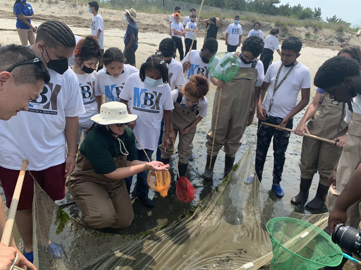 Marissa DeBonis, Environmental Educator Assistant at the Jones Beach Energy & Nature Center, shows a group of students wildlife that were caught during a beach seining activity at the West End Boat Basin at Jones Beach State Park.
