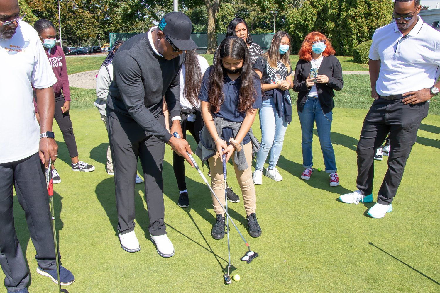 Victor Green demonstrated the art of putting while Mayor Waylyn Hobbs, Jr., left, and teacher-coach Noah Burroughs, right, looked on.