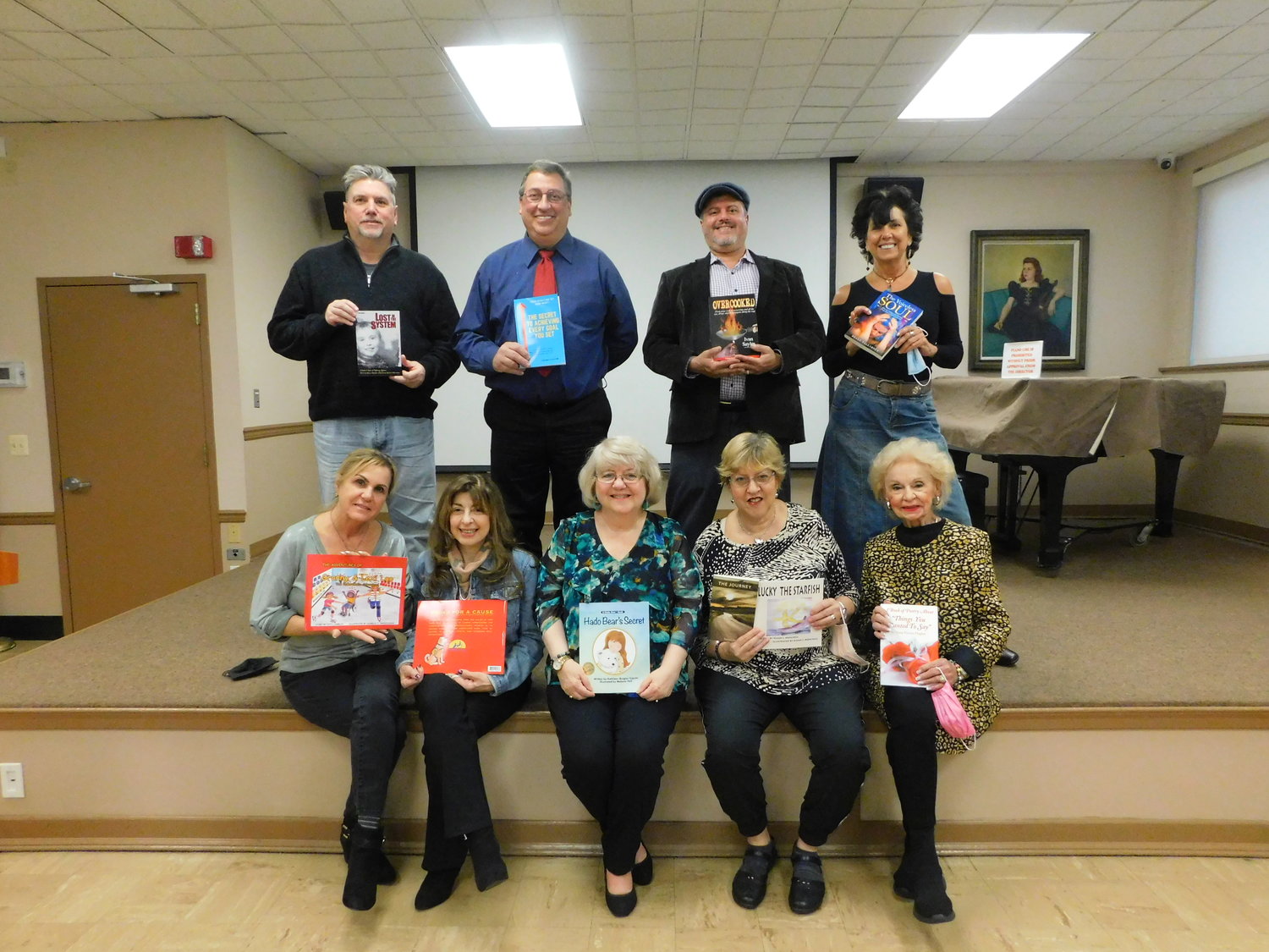 Eight members of the Long Island Author Coalition brought their works to a joint book signing event on Nov. 7. From left, standing, Tom Gibson, Stephen G. Flecker, Ivan Sayles, and Kelly Tallaksen. Seated, Patti Damelio with illustrator Isabelle Rappaciuolo, Kathleen Quigley Caputo, Susan J. Menchell, and Maria V. Hughes.