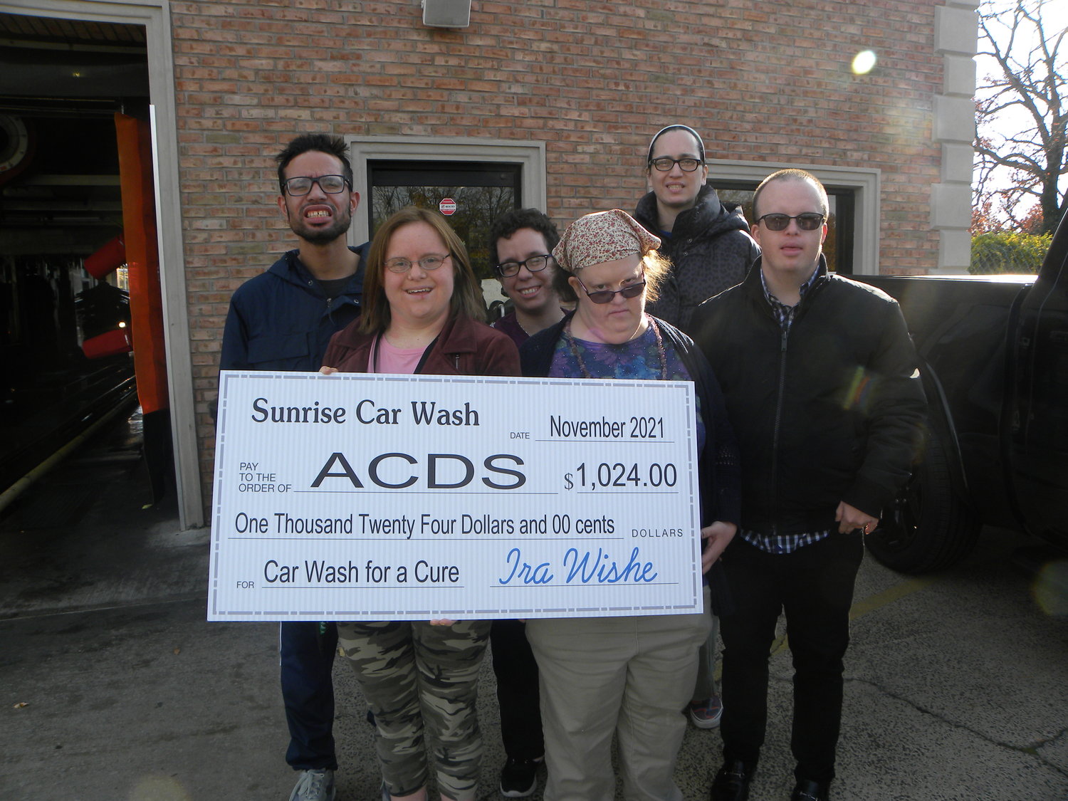 ACDS attendees with the ceremonial check at the Sunrise Car Wash. ACDS has a day habilitation center and numerous group homes in Merrick.