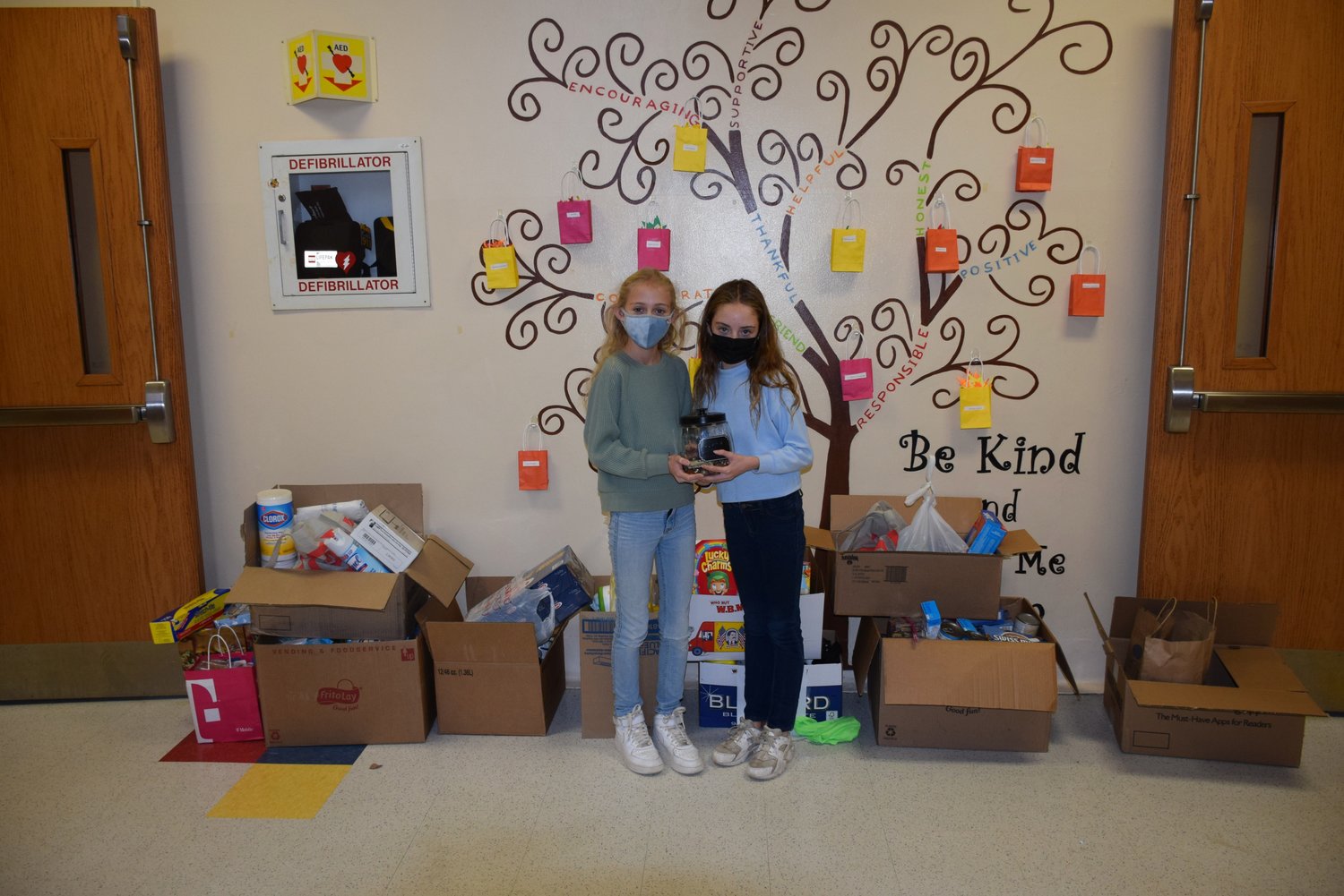 Student Council President Grace Cohn and Vice President Abby Burleigh in front of the John Lewis Child’s School’s kindness tree with the donations the student council raised for Ronald McDonald House Charities