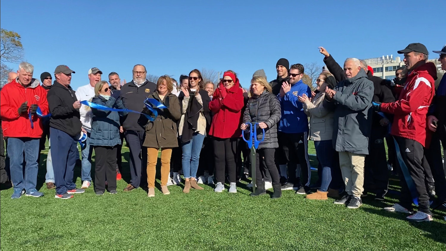 Kathleen Tighe, center right, with scissors, cut the ribbon on the new Tighe Field. Her late husband, Stephen, touched the lives of many soccer players in Rockville Centre.