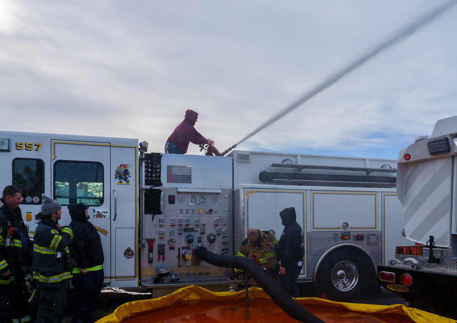 A large black hose on the side of a fire truck, left, is used to suck the water out of the pool and then to put out a fire.